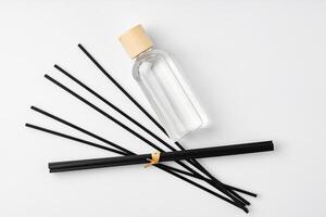 A minimalist display of essential oil and black diffuser sticks on a clean white background photo