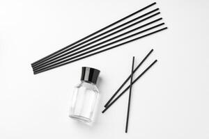 A minimalist display of essential oil and black diffuser sticks on a clean white background photo