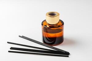 A minimalist display of essential oil and black diffuser sticks on a clean white background photo