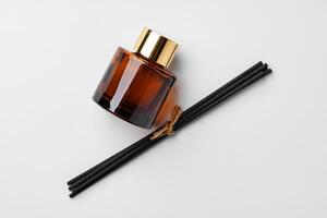 A minimalist display of essential oil and black diffuser sticks on a clean white background photo