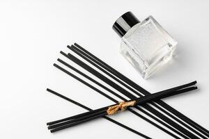 A minimalist display of essential oil and black diffuser sticks on a clean white background photo