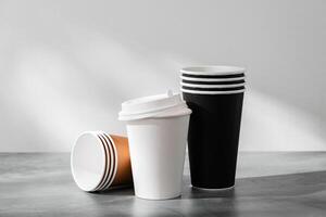 Stack of coffee cups in various colors with lids on a gray surface photo