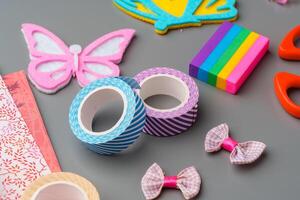 Crafting supplies arranged for a DIY project on a gray table with scissors, washi tape, and decorative items photo