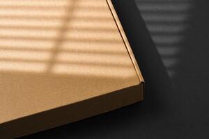 A cardboard box casting shadows on a dark surface in a striped light pattern photo