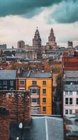 Yellow building stands out among rooftops with historic architecture in urban skyline on a cloudy day photo