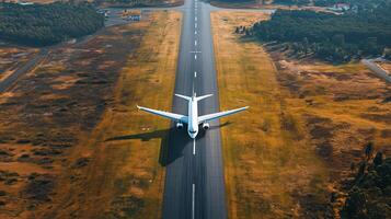 Airplane taking off from a runway surrounded by lush greenery and fields during a bright and clear day photo