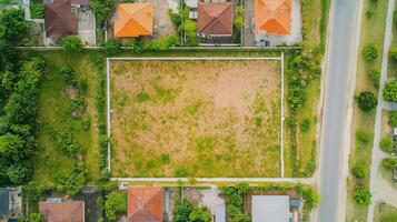 Aerial view of an empty plot of land surrounded by residential houses on a sunny day photo