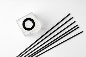 A minimalist display of essential oil and black diffuser sticks on a clean white background photo