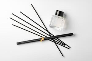 A minimalist display of essential oil and black diffuser sticks on a clean white background photo