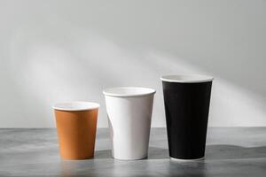 Stack of coffee cups in various colors with lids on a gray surface photo
