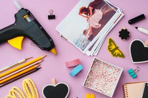 Crafting supplies arranged on a pink background, including glue gun, scissors, and decorative items for DIY projects photo