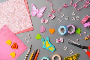 Crafting supplies arranged for a DIY project on a gray table with scissors, washi tape, and decorative items photo