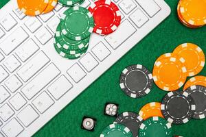 Chips and playing cards on a green felt surface near a computer keyboard during an online gaming session at home photo