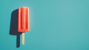 Bright red popsicle on a turquoise background adds a refreshing touch to a sunny day in summer photo