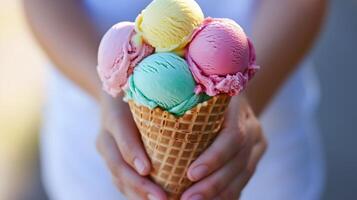 A person holds a colorful ice cream cone with four scoops at a summer event in a sunny outdoor setting photo