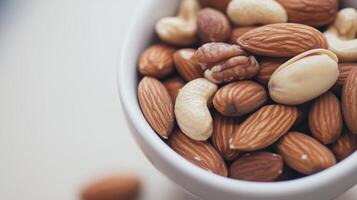 A variety of mixed nuts in a white bowl on a light surface ready for snacking and healthy eating at home photo