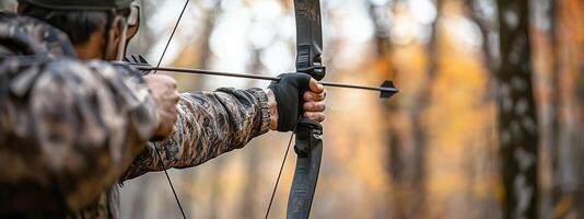 An archer focuses intently while aiming in a serene forest during autumn, capturing the essence of outdoor archery practice photo