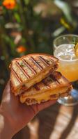Delicious grilled cheese sandwich served with a refreshing drink in a vibrant outdoor setting photo