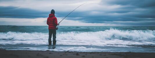 A person fishing on a shoreline under a cloudy sky during early evening at a tranquil beach photo