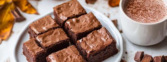 Delicious homemade brownies served with a warm cup of cocoa on a rustic table with autumn leaves in the background photo