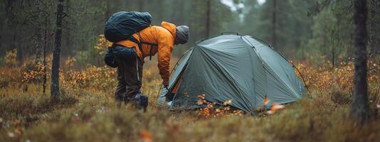 Camping enthusiast sets up a tent in the tranquil forest during autumn, surrounded by colorful foliage and soft morning light photo