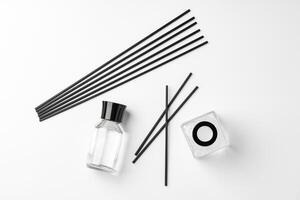 A minimalist display of essential oil and black diffuser sticks on a clean white background photo