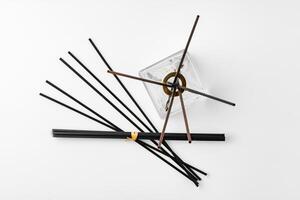 A minimalist display of essential oil and black diffuser sticks on a clean white background photo