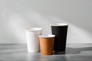 Stack of coffee cups in various colors with lids on a gray surface photo