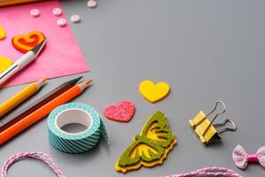 Crafting supplies arranged for a DIY project on a gray table with scissors, washi tape, and decorative items photo