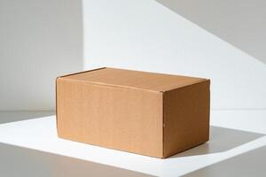 Simple brown cardboard box positioned on a white surface with soft angled shadows in natural light photo