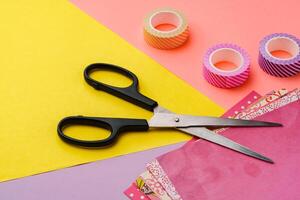 Scissors and decorative tape on colorful craft paper in a bright workspace photo