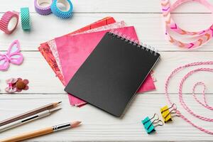 Crafting essentials on a workspace featuring a black notebook, colorful paper, and decorative supplies photo
