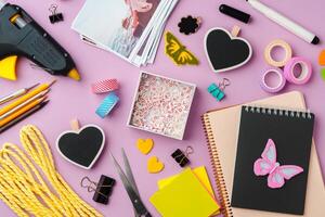Crafting supplies arranged on a pink background, including glue gun, scissors, and decorative items for DIY projects photo