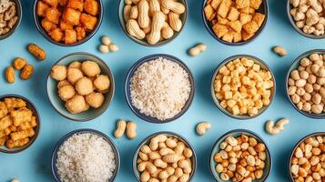 A vibrant assortment of snacks including rice, nuts, and savory bites arranged on a blue tablecloth in a casual setting photo