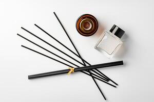 A minimalist display of essential oil and black diffuser sticks on a clean white background photo