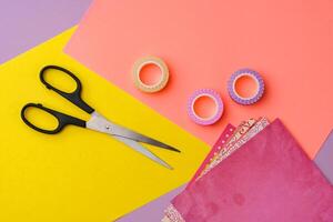 Scissors and decorative tape on colorful craft paper in a bright workspace photo