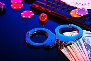 Handcuffs placed beside cash and poker chips on a black table at a dimly lit gambling setting photo