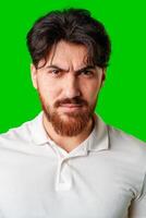 A young man with a beard showing a serious expression against a vibrant green background photo