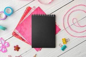 Crafting essentials on a workspace featuring a black notebook, colorful paper, and decorative supplies photo