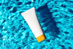 Sunscreen bottle floating in a clear blue swimming pool on a sunny day photo