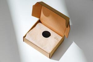 A small, empty cardboard box with unwrapped parchment resting inside on a bright, sunlit table photo