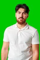 A man with a serious expression stands against a vibrant green background photo