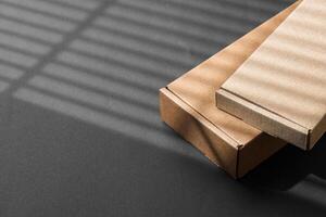 Various sizes of brown cardboard boxes arranged on a black surface with soft lighting effects during the day photo