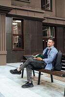 A person writes in a notebook while sitting on a park bench photo