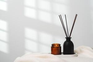 Elegant Aroma Diffuser With Reed Sticks And Scented Candle On White Tablecloth photo