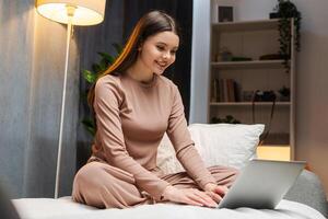 Young girl, teenager working remotely from home office using laptop computer photo
