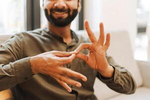 Smiling man using sign language communicating, selective focus on hands photo