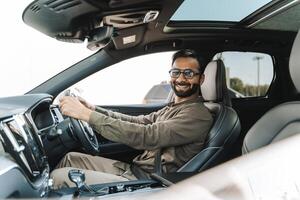 Happy Indian businessman smiling while driving modern car looking at camera photo