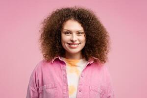 retrato de atractivo sonriente mujer con Rizado pelo vistiendo elegante camisa, mirando a cámara foto