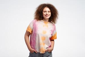 hermosa sonriente joven mujer con Rizado pelo vistiendo elegante verano t camisa mirando a cámara foto